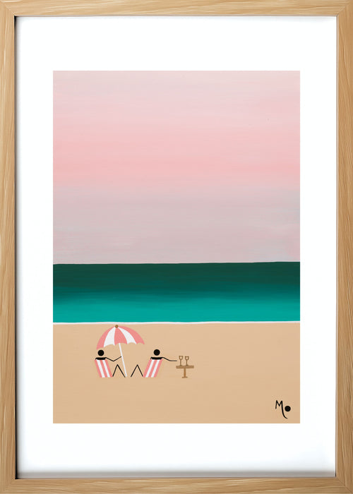 Blue Cocktail Hours captures two people enjoying drinks together on the beach as day slowly fades into night. Soft tones of pink and blue wash across the sky and ocean, creating a peaceful and dreamy twilight atmosphere. Light Wood Framed
