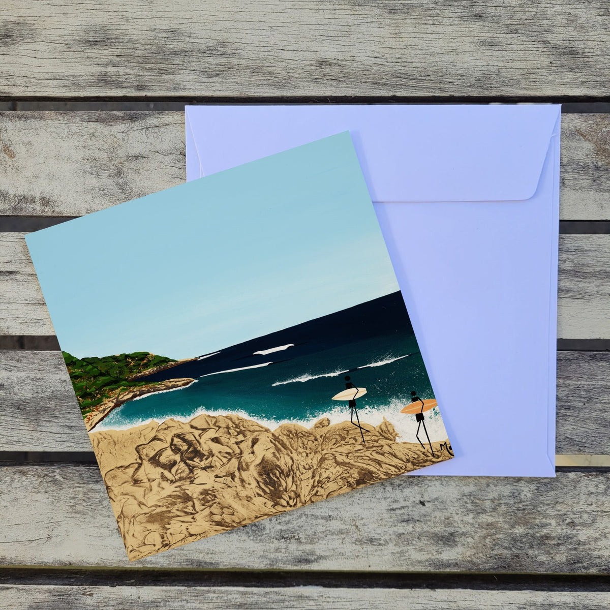 Card featuring an original artwork inspired by Huzzas, a much-loved surf break in Gracetown Bay, Western Australia, capturing the peaceful atmosphere and beauty of this special corner of the Margaret River coast and a white envelope placed behind it on a weathered wood surface.