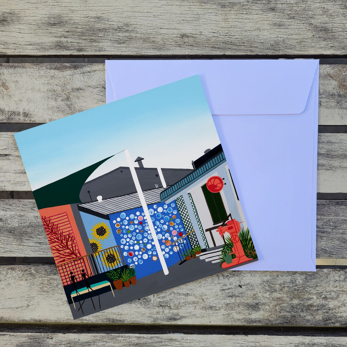 Featuring an original artwork inspired by the Margaret River Bakery, a quirky and much-loved local spot in the heart of town, known for its unique charm, character and relaxed atmosphere. Placed over a white envelope on a rustic weathered wood surface.